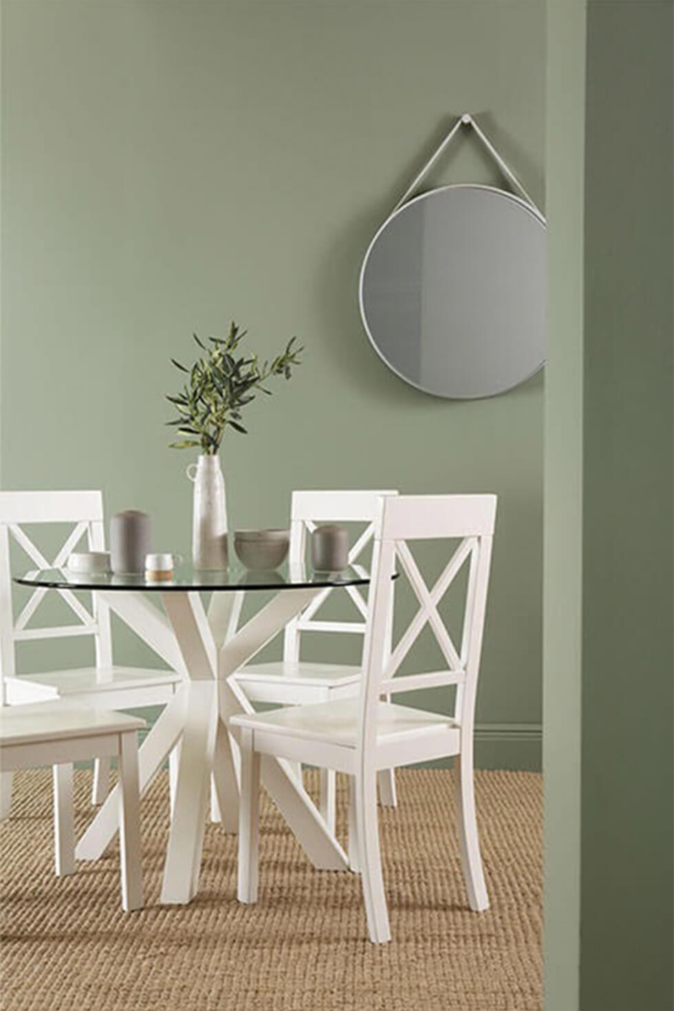 round white and glass dining table in a contemporary sage green dining room