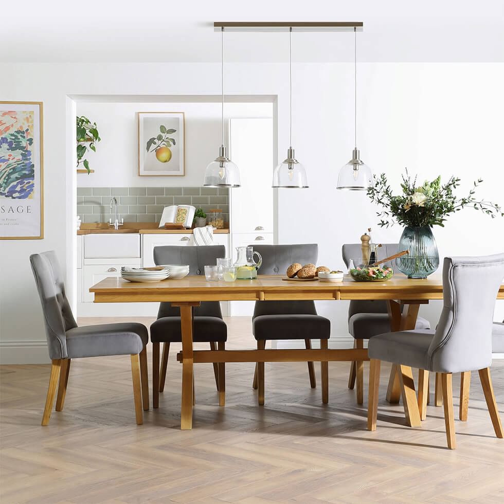 Wooden dining table with grey dining chairs in light airy dining room