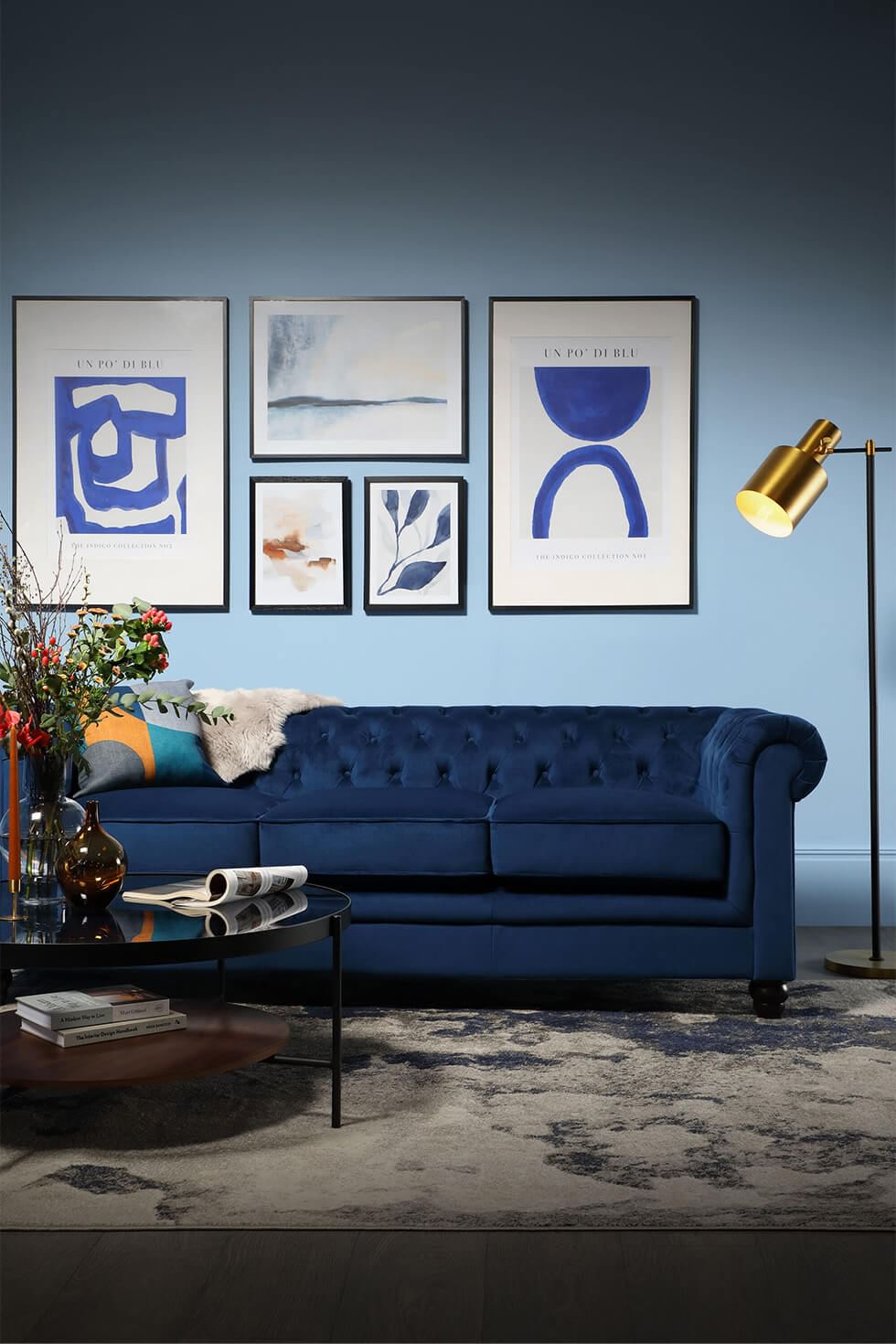 Modern living room featuring a gallery wall and blue velvet sofa