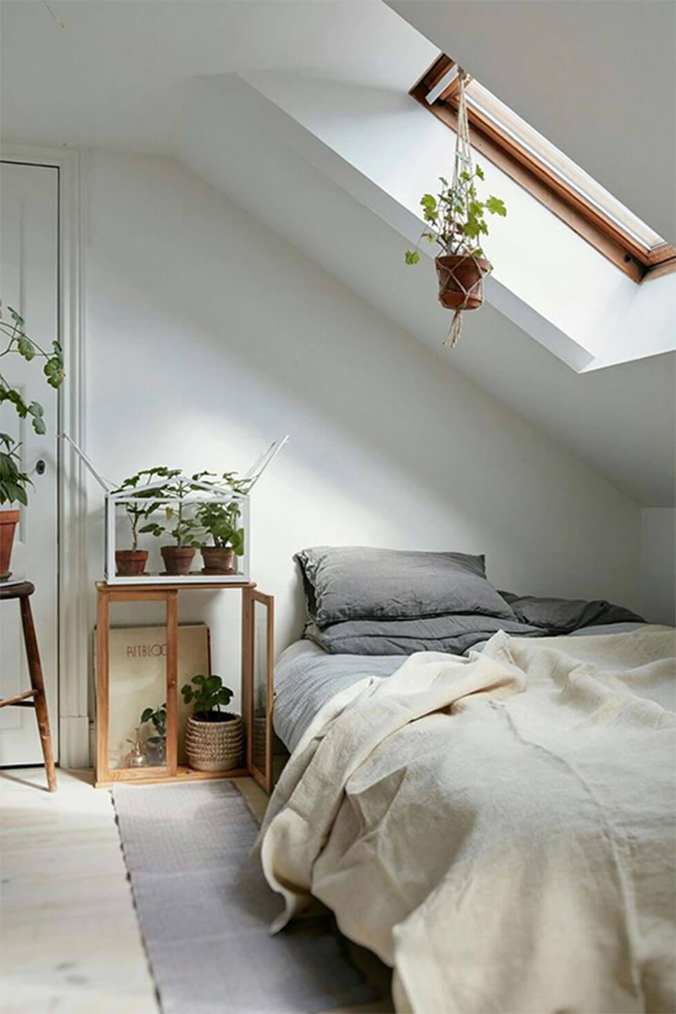 Neutral loft bedroom with grey pillows, white bedding and greenery