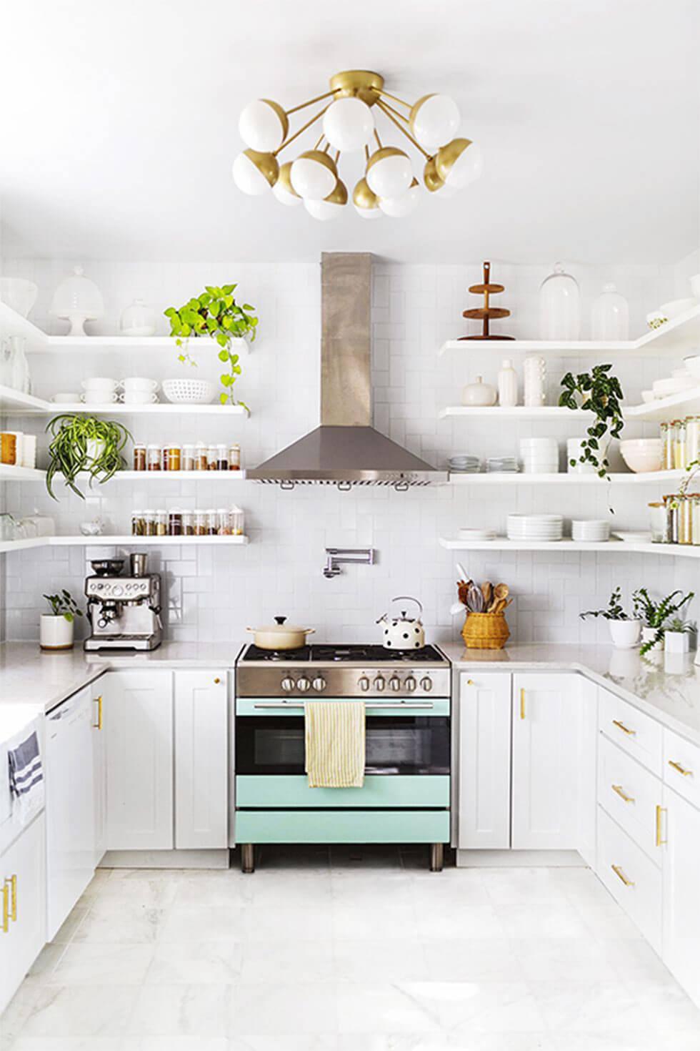 Small white kitchen with shelves on walls, a light blue oven, and a statement gold lamp