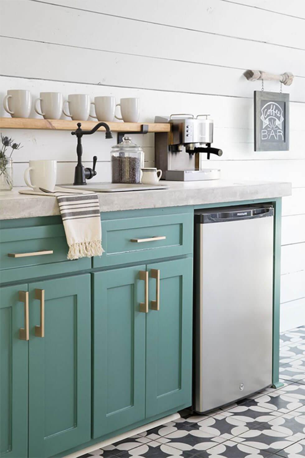 Simple white small kitchen with shiplap walls, teal cabinets with gold handles, and geometric floor tiles