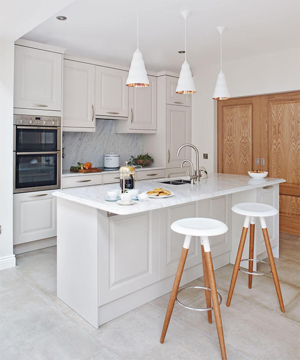 Airy white small kitchen with a kitchen island, wooden bar stools and a tall cupboard