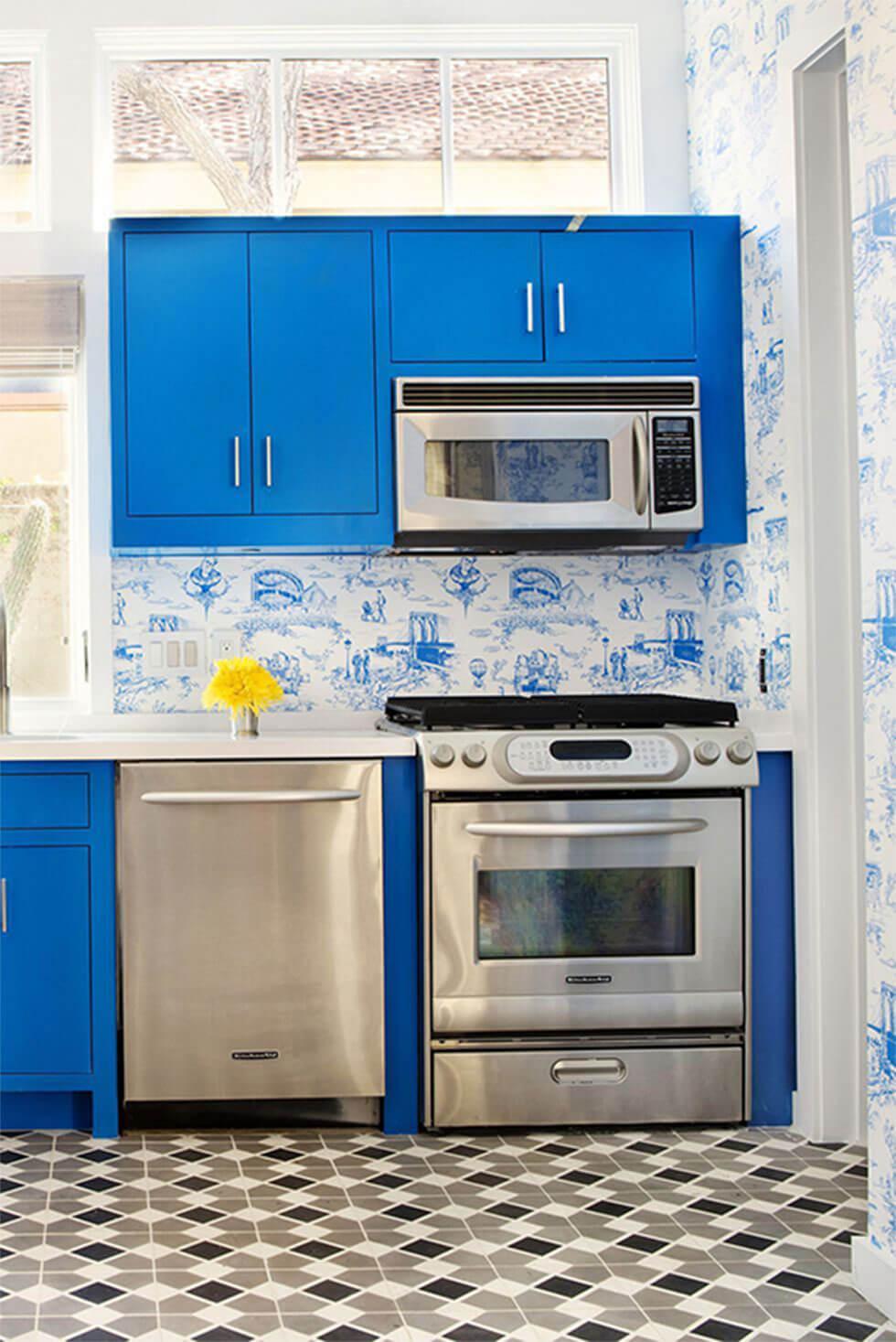 Small kitchen with statement blue cabinets, chrome appliances, geometric tiles and blue floral wallpaper