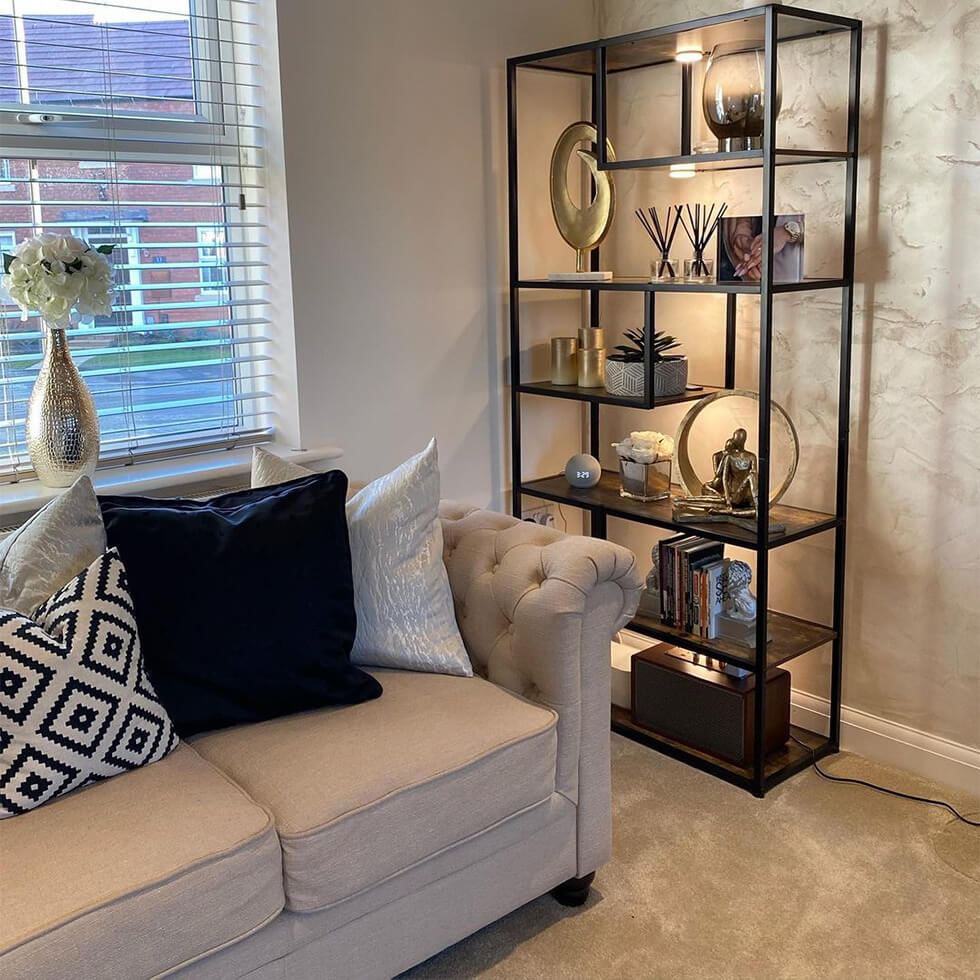 Cosy living room with a fabric sofa and bookshelf full of accessories