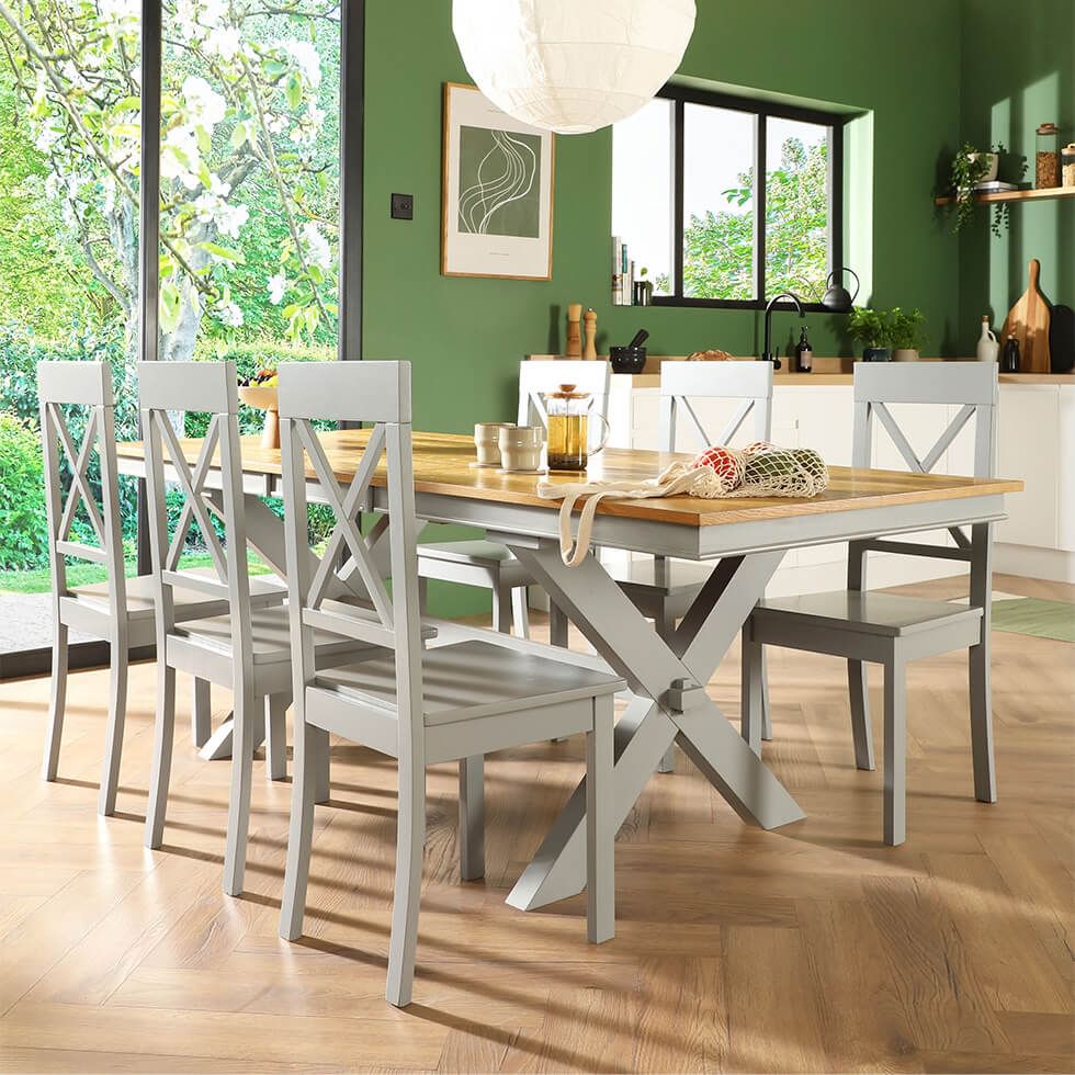 Grey painted wooden dining set in an open plan kitchen with green walls