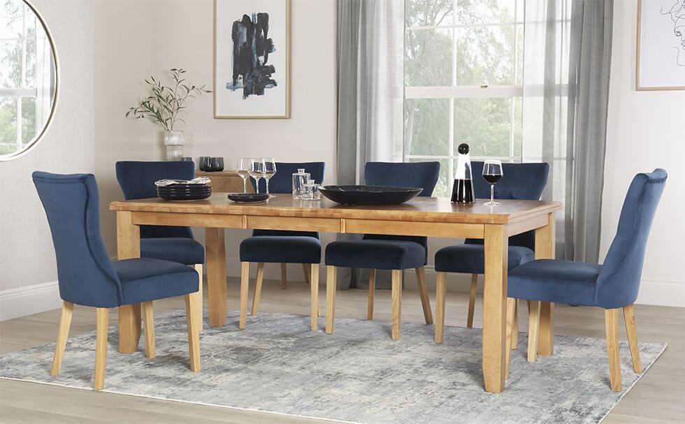 Coastal style grey dining room with blue dining chairs and a wood dining table