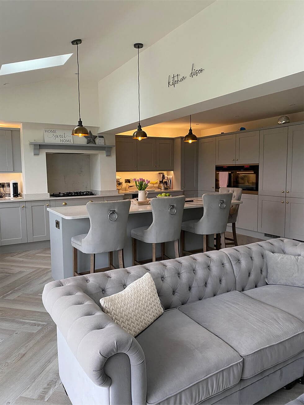 Grey barstools, grey kitchen counters, and a grey sofa in an open plan grey dining room
