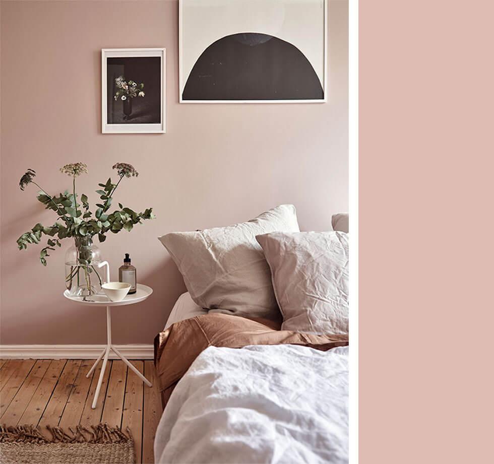 Dusky pink bedroom with bedding, bedside table and artwork