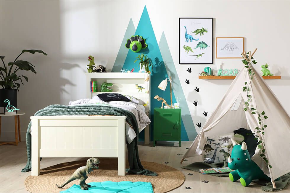 Cute dinosaur-themed bedroom with mountain backdrop and dino decals and soft toys