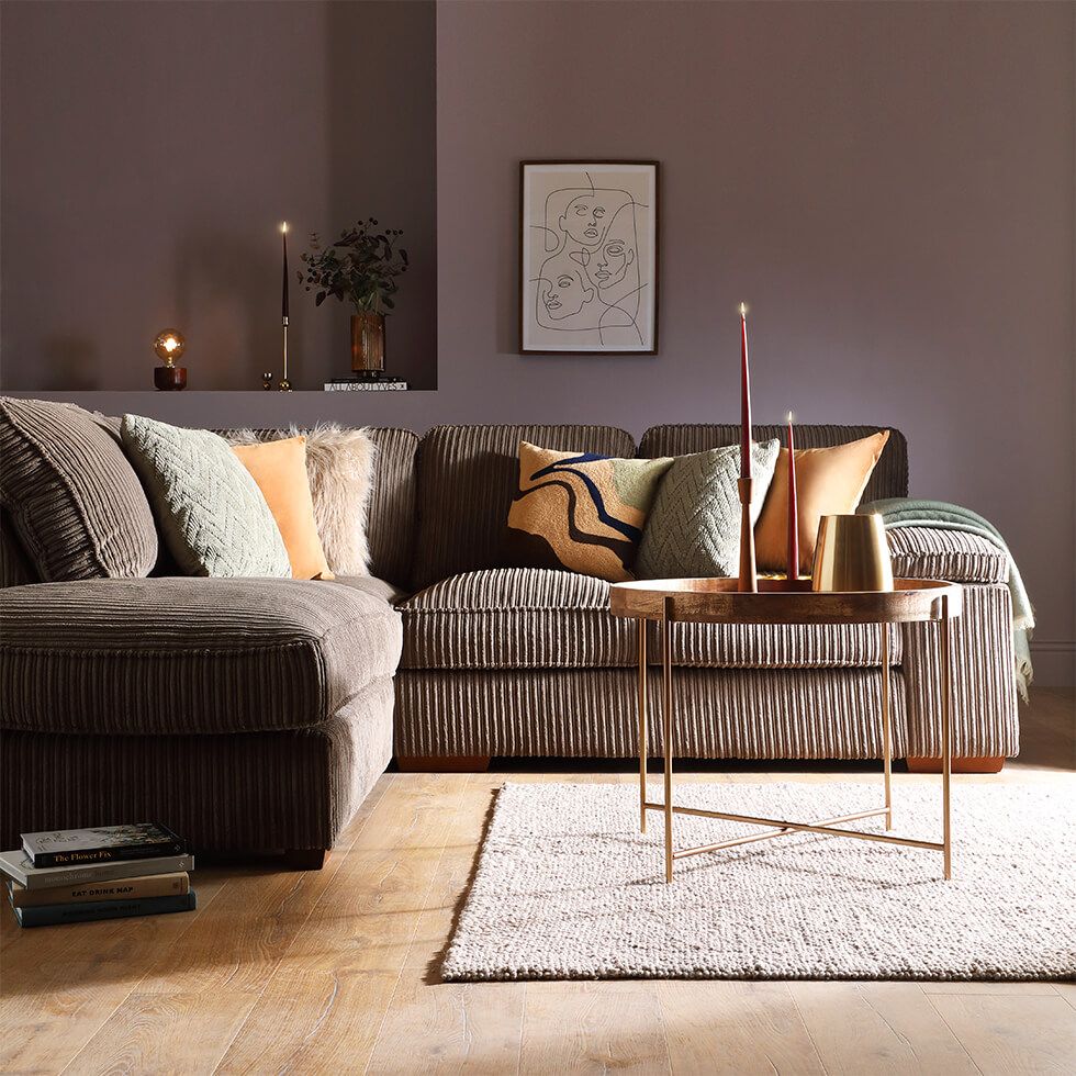A mink brown cord sofa with scatter cushions in a cosy living room