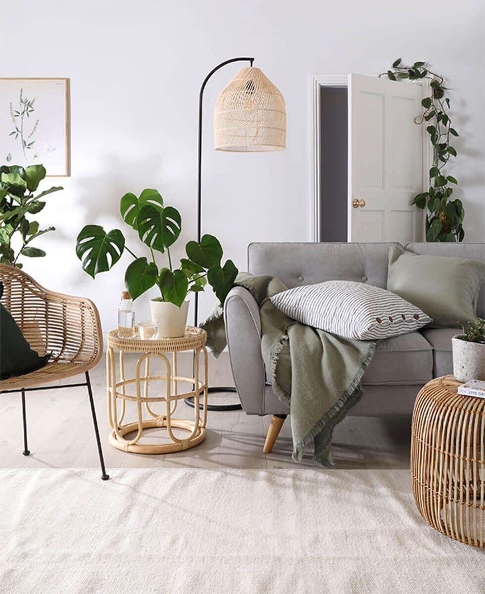 Modern bohemian living room with grey sofa, rattan accessories and indoor plants