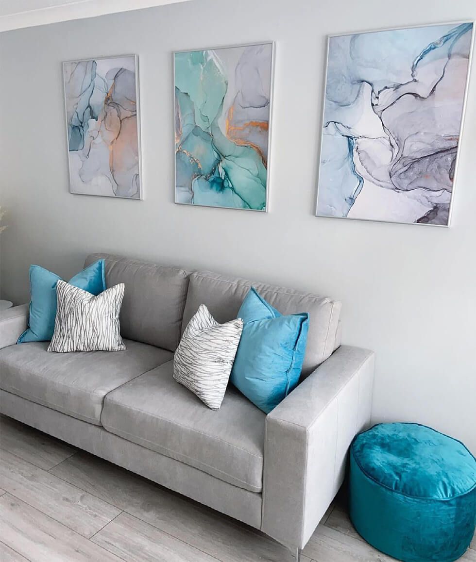 Modern living room with a grey sofa, turquoise cushions and abstract wall art
