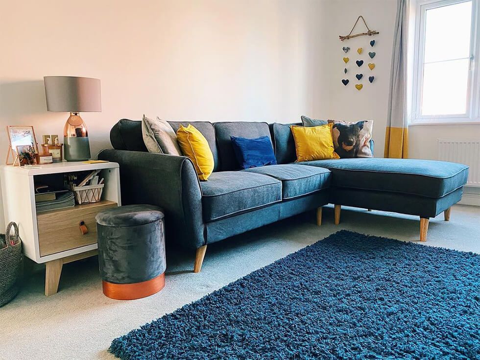 Fun living room with a corner sofa, yellow accessories and a shaggy blue rug