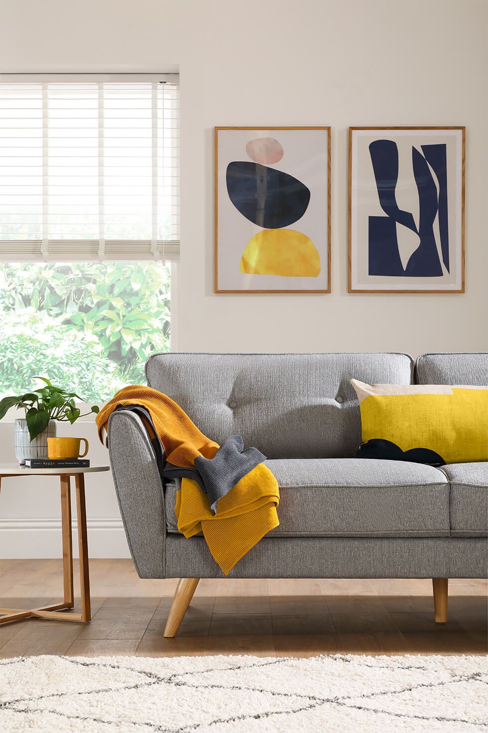 Bright living room with a grey sofa, yellow accessories and abstract wall art