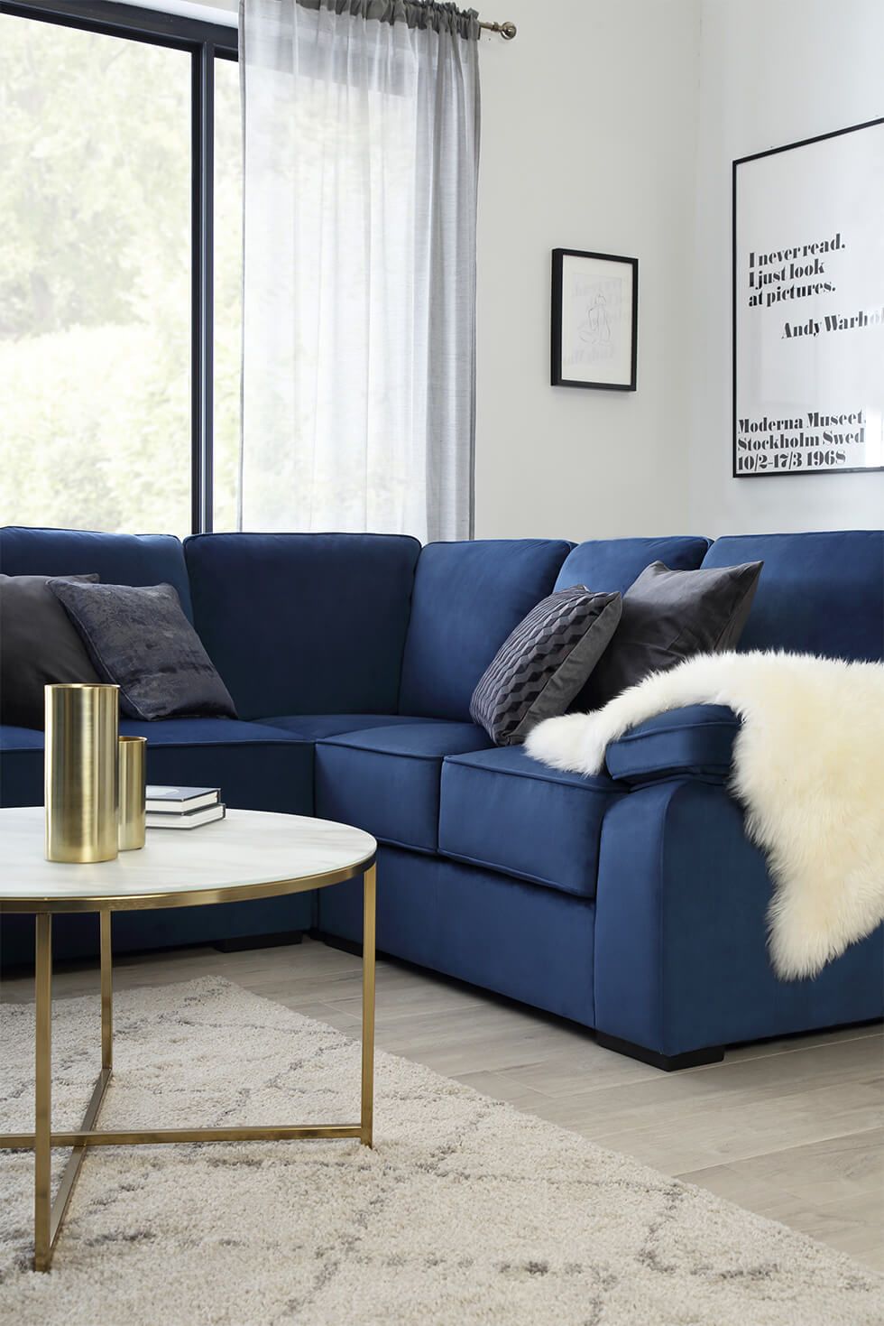 Minimalist living room with a navy corner sofa and slim gold coffee table