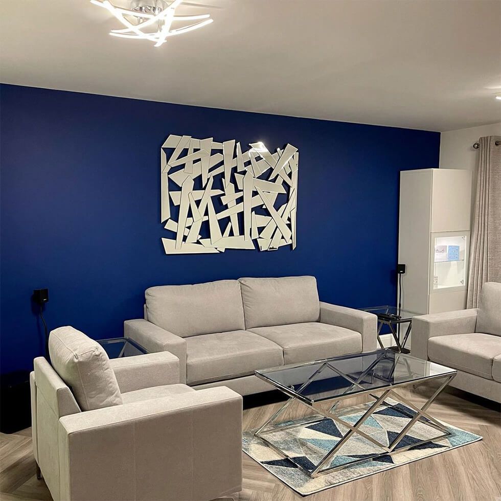 Modern living room with a grey sofa, turquoise cushions and abstract wall art