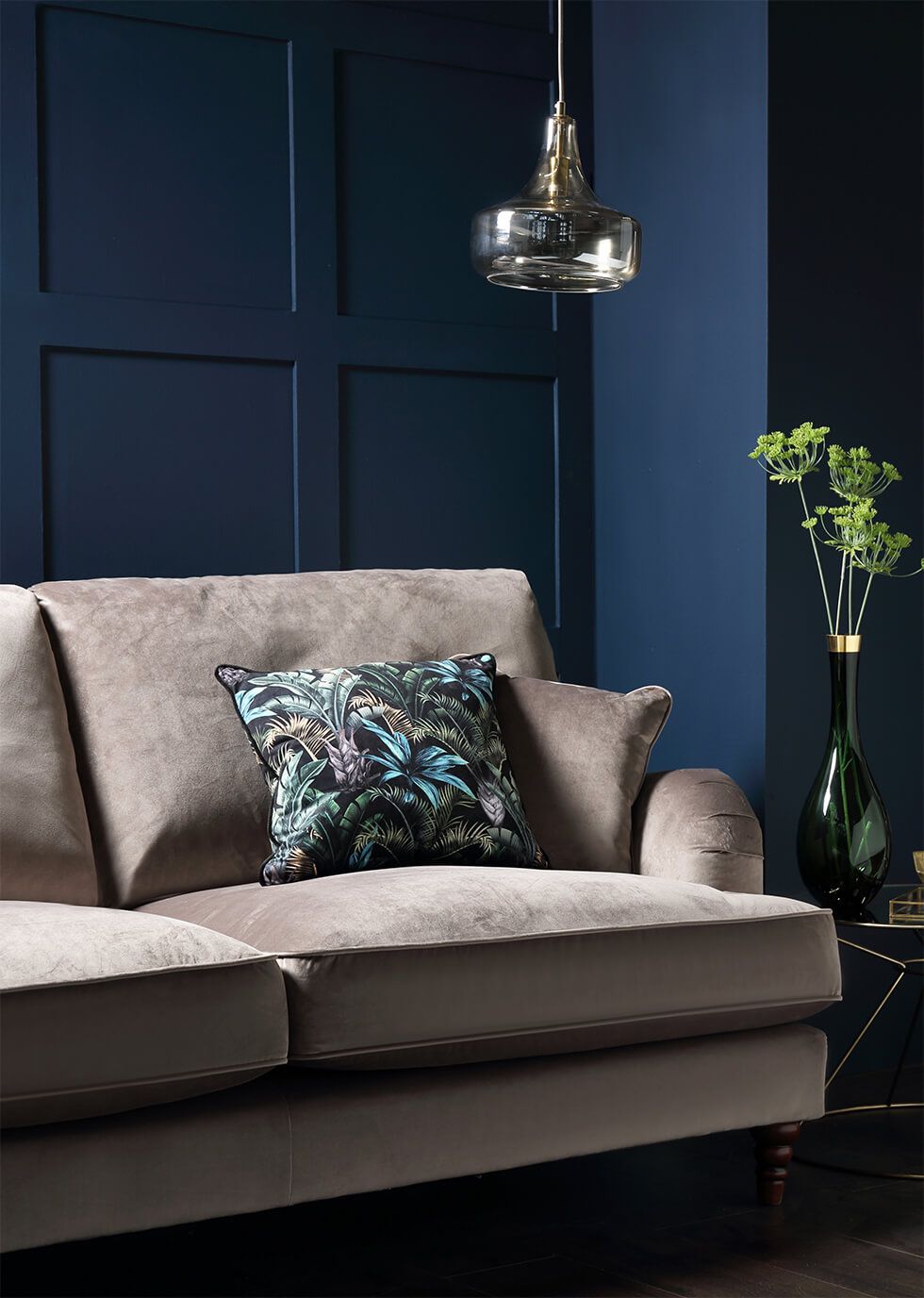 Sophisticated living room with a navy wood-panelled accent wall, grey sofa and pendant lamp