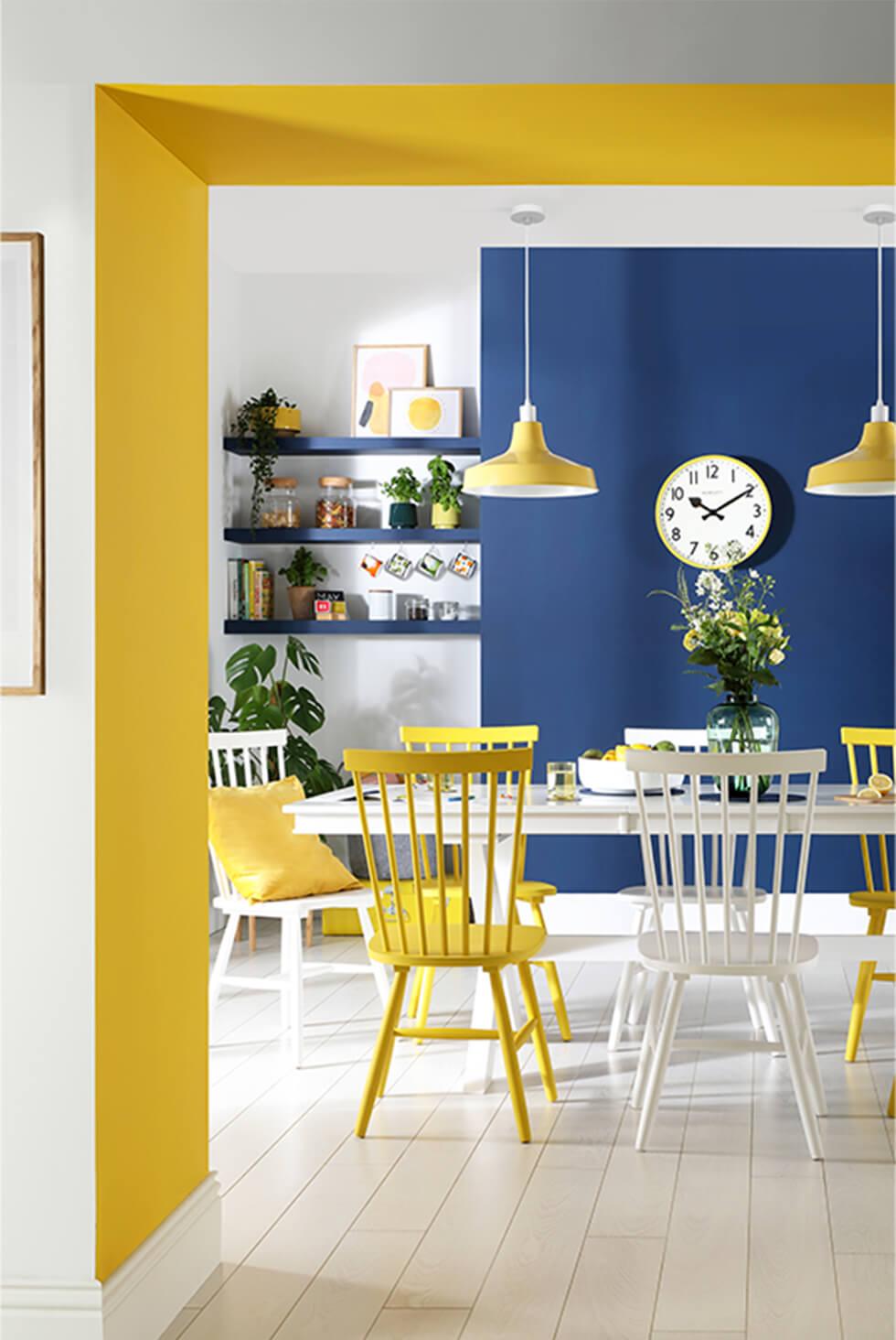 Mismatched white and yellow dining chairs with blue and yellow accent walls