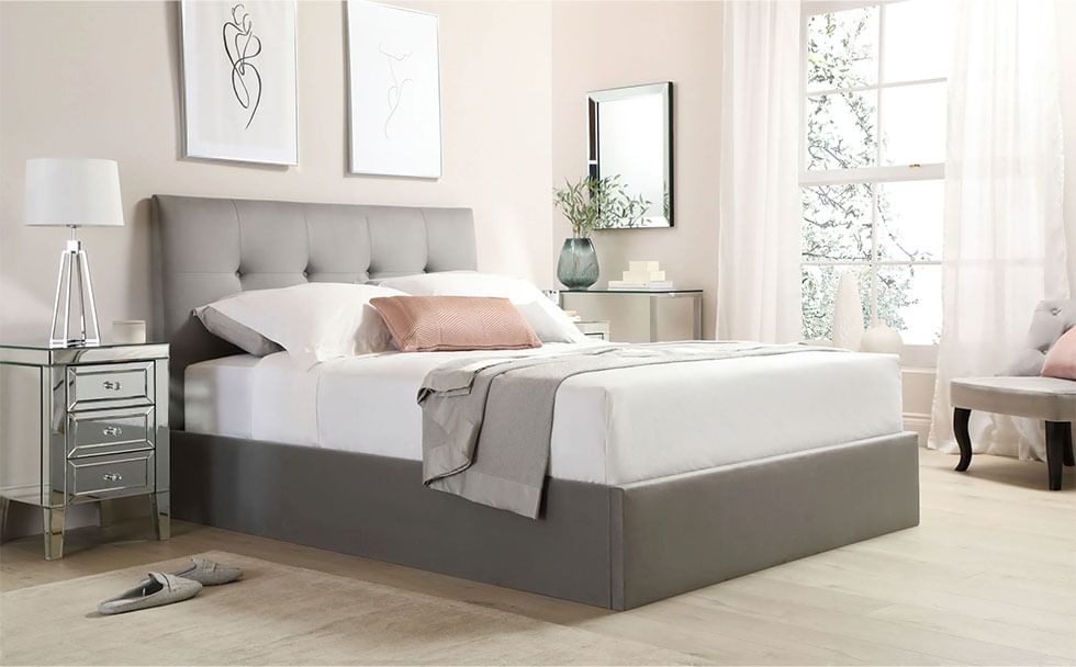 Grey velvet ottoman bed and mirrored bedside drawers in a modern and airy bedroom