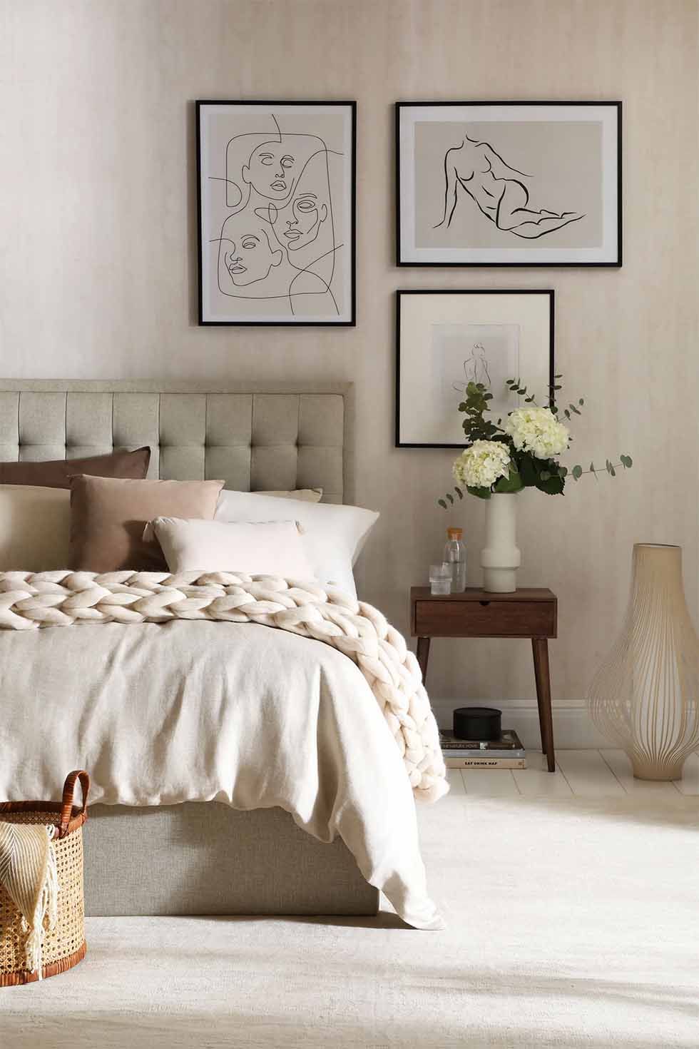 Oatmeal fabric bed layered with pillows and a chunky knit throw in a cosy contemporary bedroom