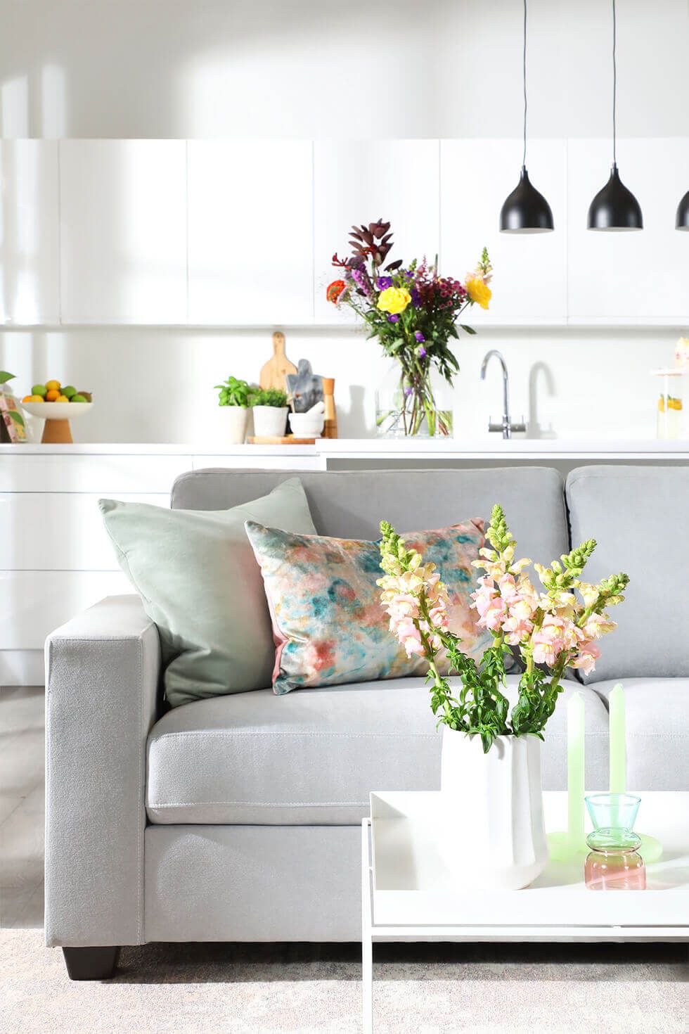 White living room with light grey sofa and floral bouquets