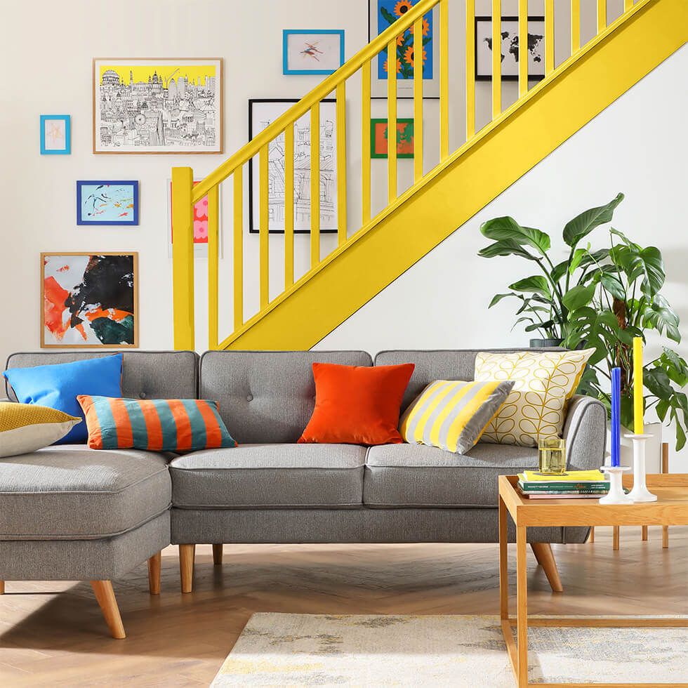 Living room with grey fabric sofa, colourful staircase and accessories