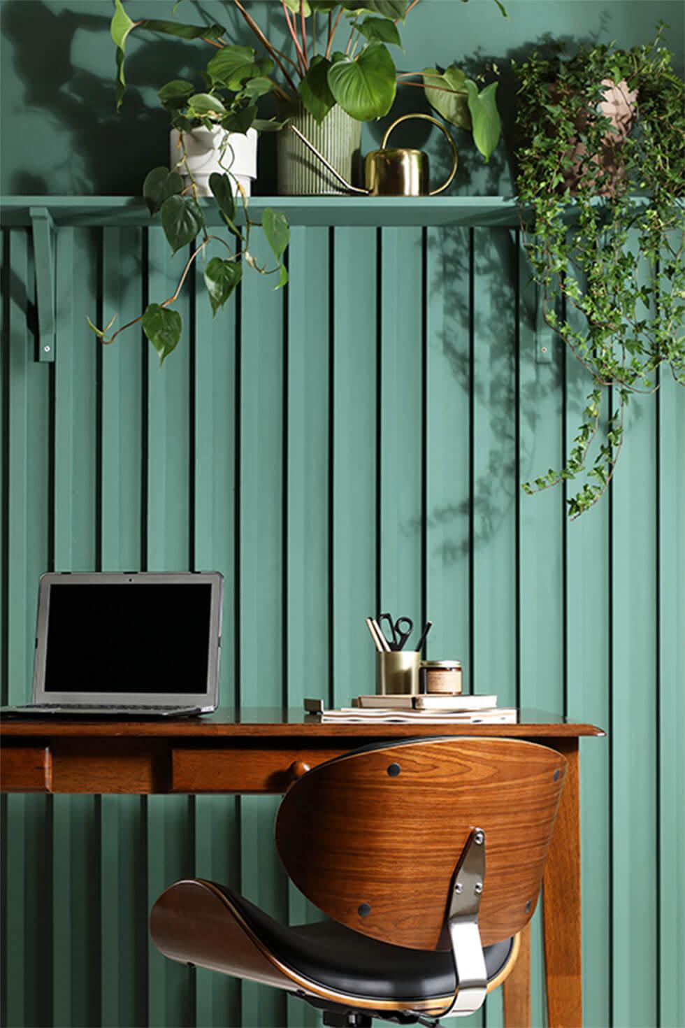 Green home office with plants and a wooden desk