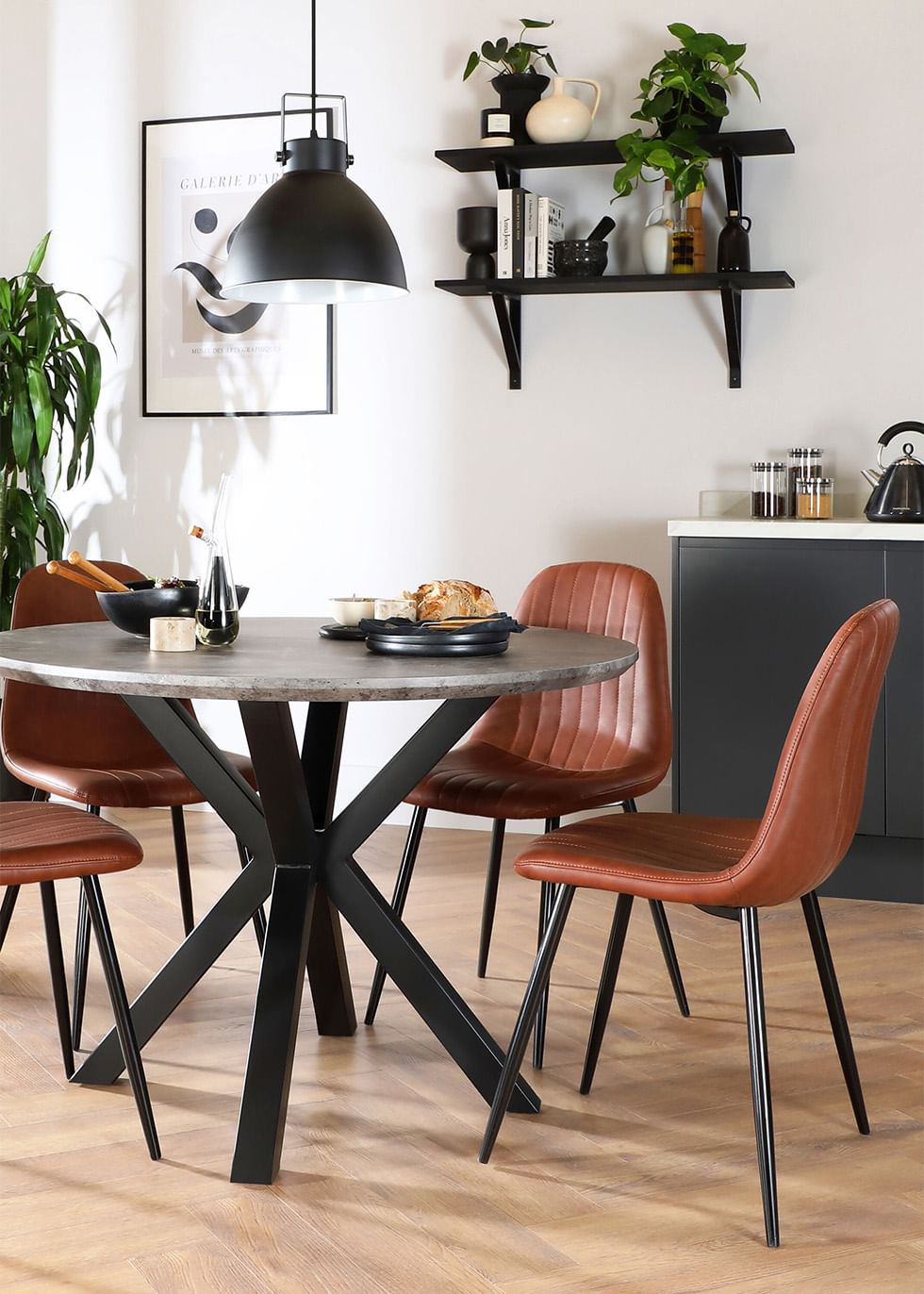 Round concrete and metal dining table with leather dining chairs