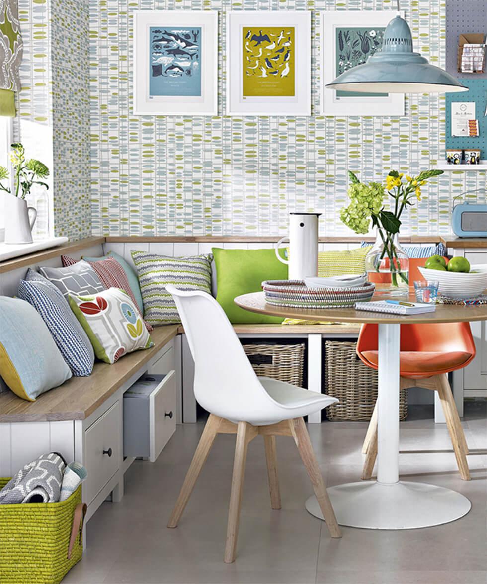 Bright and colourful dining room with built in bench with baskets and drawers beneath, and a round table.