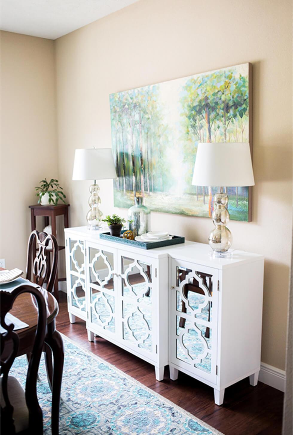 Modern mirrored sideboard in white with white lamps, and a dark wood dining set