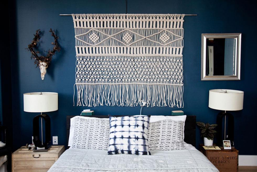 A bohemian style bedroom wall with a knotted macrame hanging.