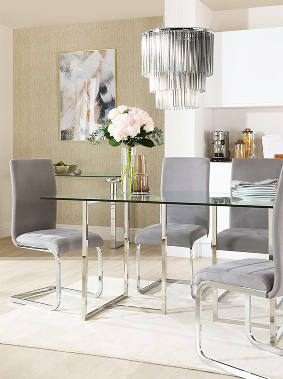 Glam chrome and glass dining room with grey velvet chairs and statement chandelier