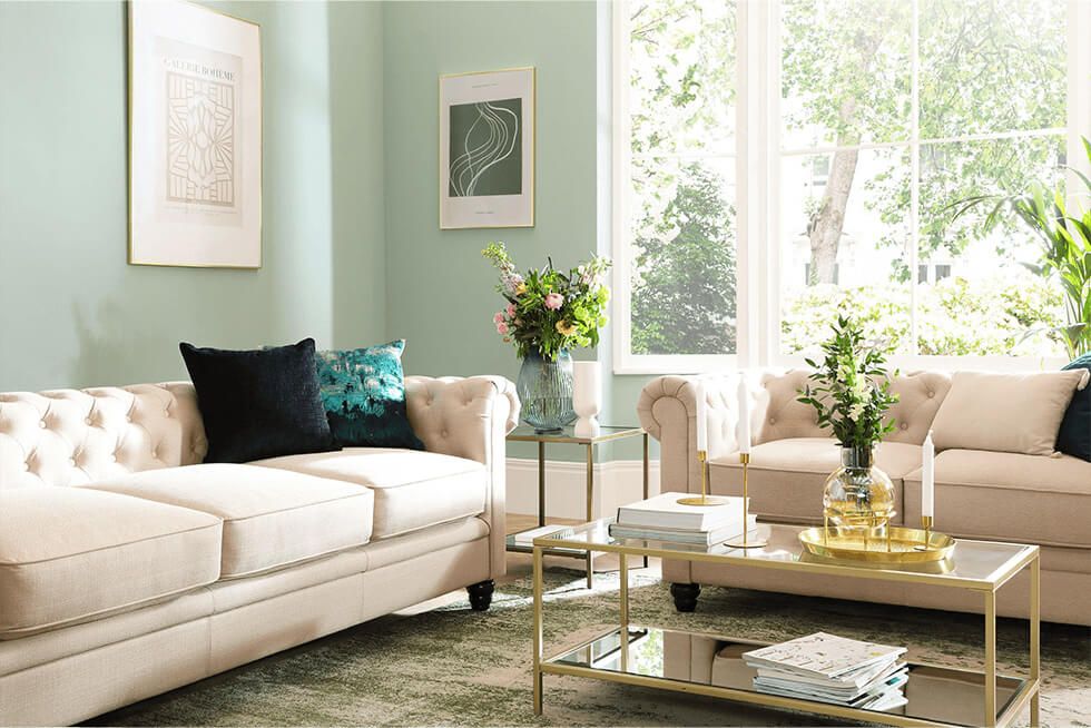 Earth tone living room with green walls and beige Chesterfield sofa