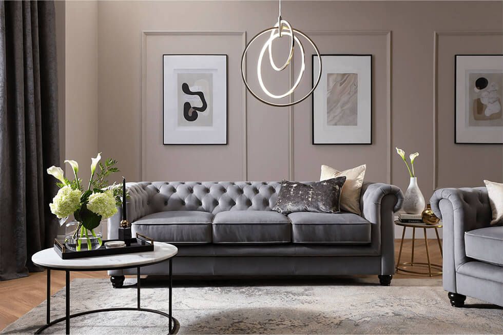 Grey velvet sofa in designer living room and earth tone walls