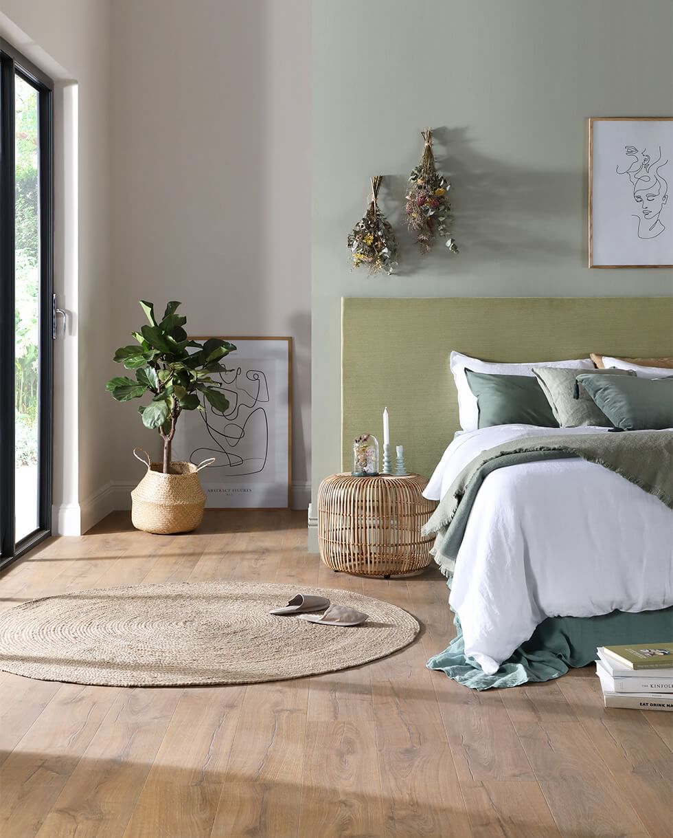 Green bedroom with natural accessories such as jute rugs, rattan and indoor plants