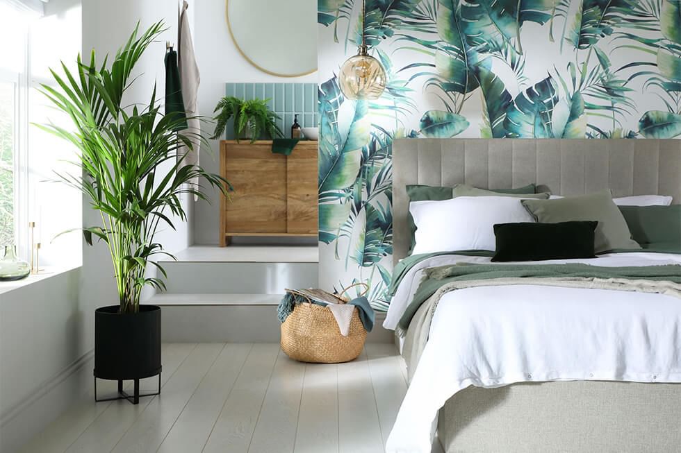 Tropical bedroom with palm print wallpaper, grey bed and indoor plants