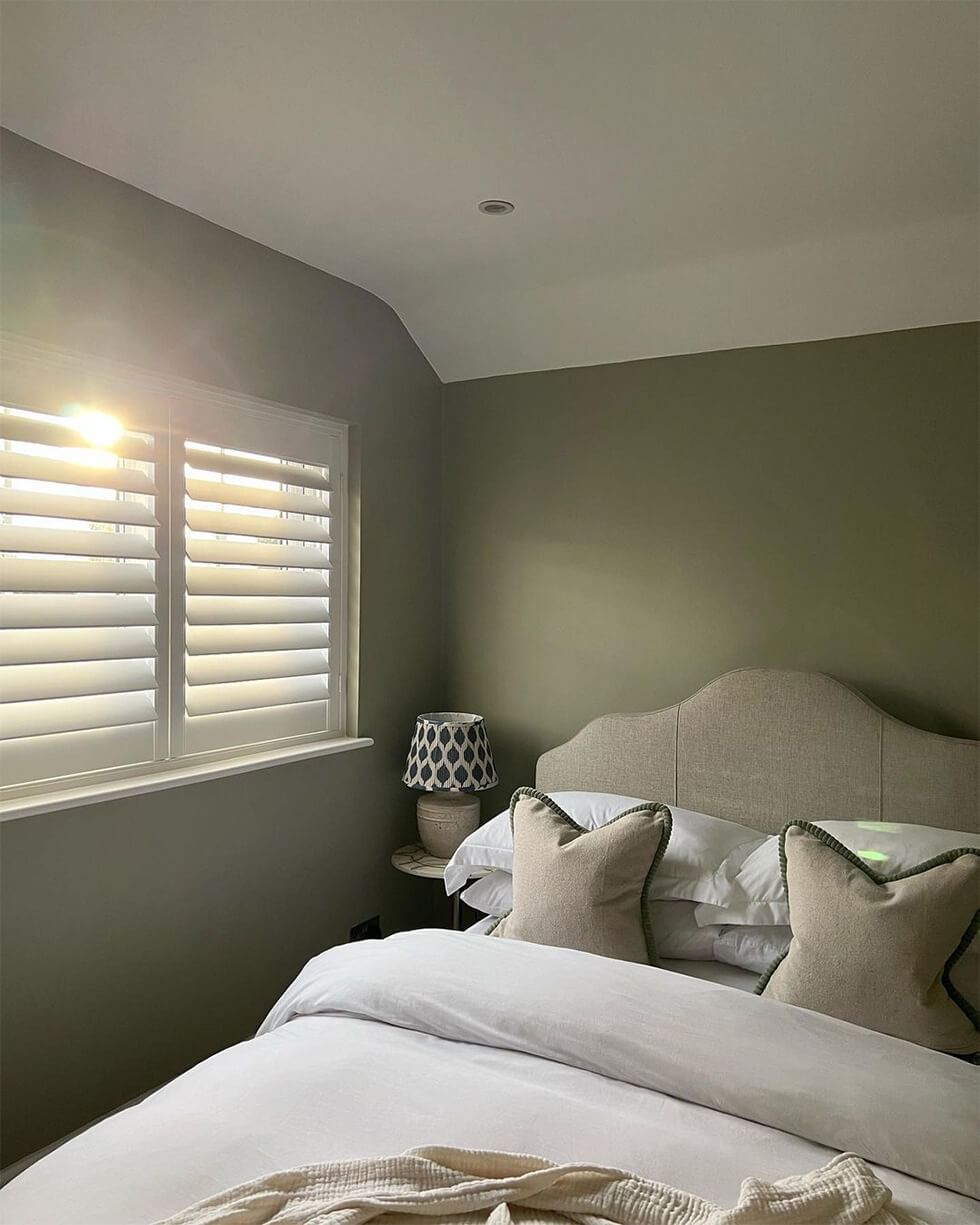 Olive green bedroom with fabric bed and neutral accessories