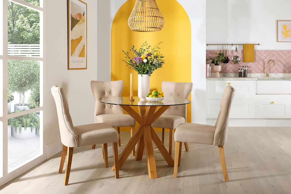 A yellow painted arch in a dining room with a round oak table and fabric chairs