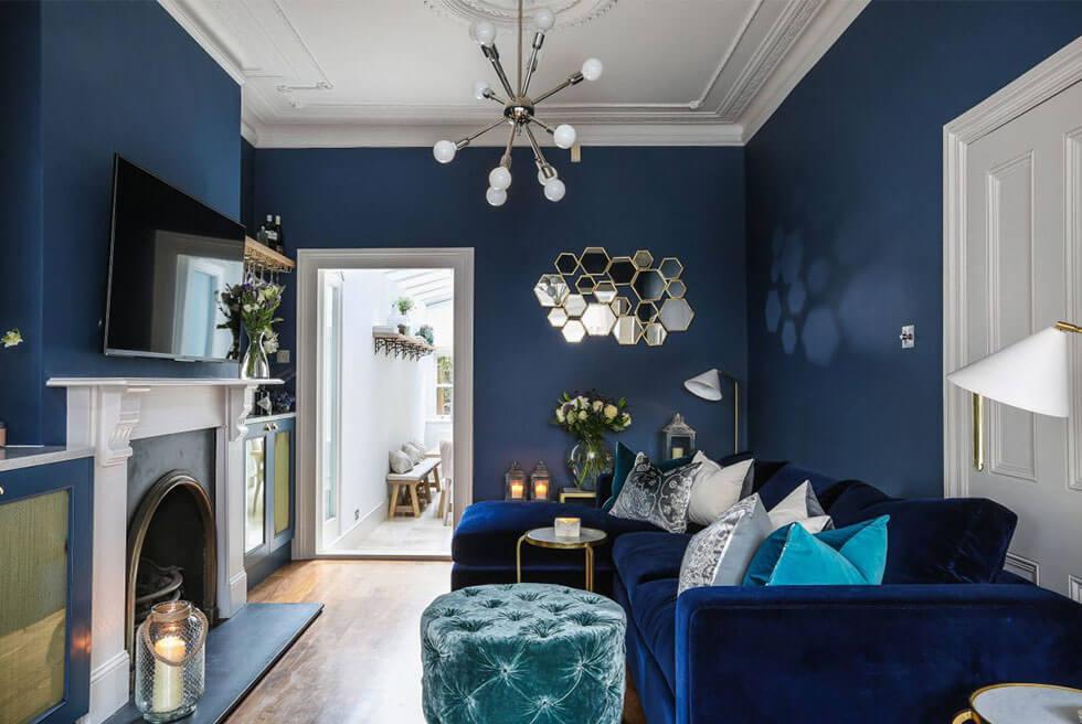 A monotone living room with a blue velvet sofa and blue walls.Blue bohemian living room with ikat fabric details.