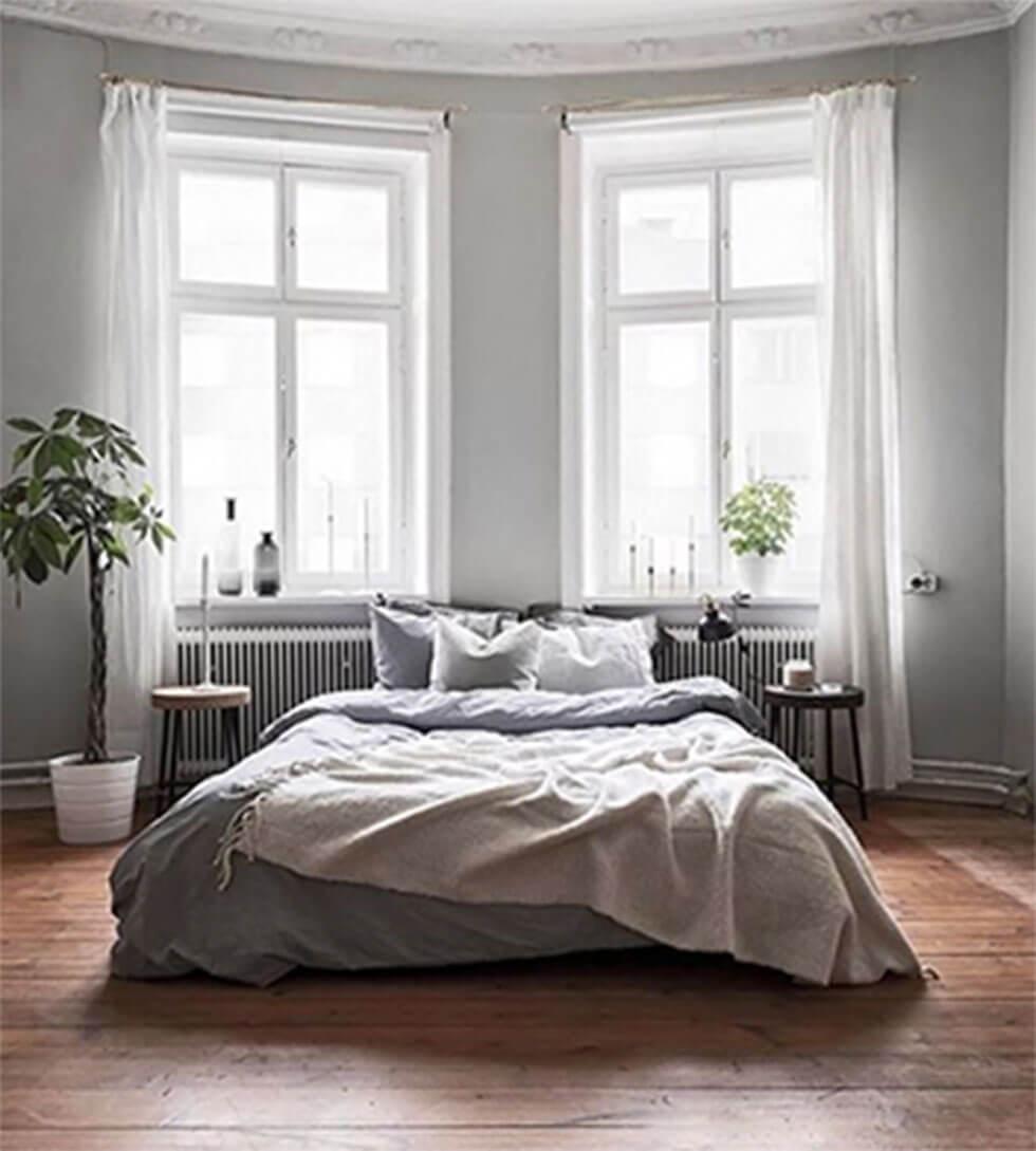 Grey bed in a grey bedroom with large windows.