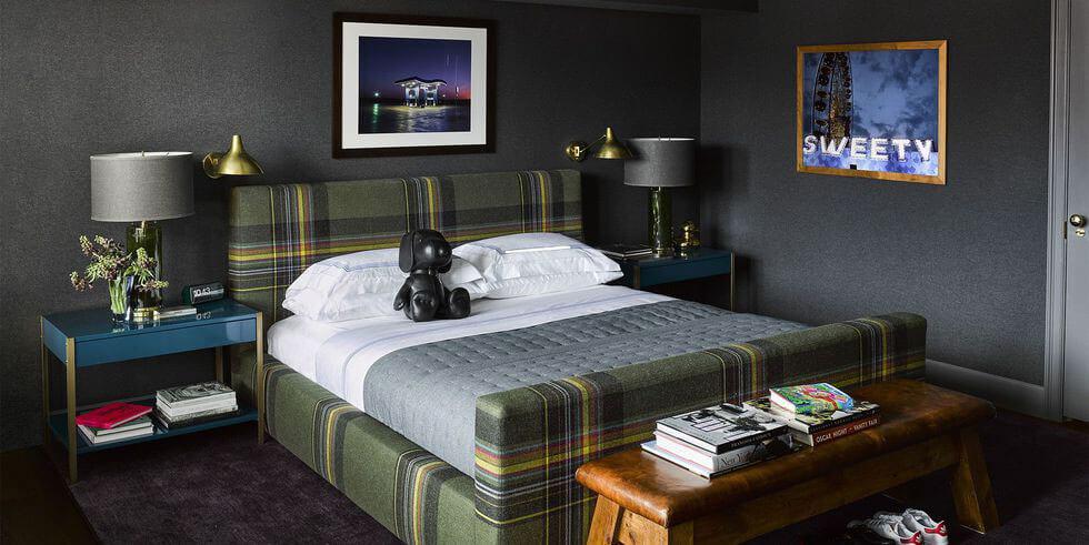 Moody dark grey bedroom with plaid green bed, modern bedside table and framed art.