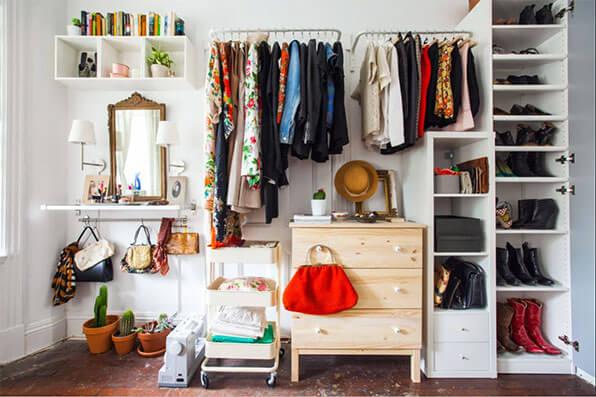 open concept wardrobe with hanging rods, hooks and a small dresser.