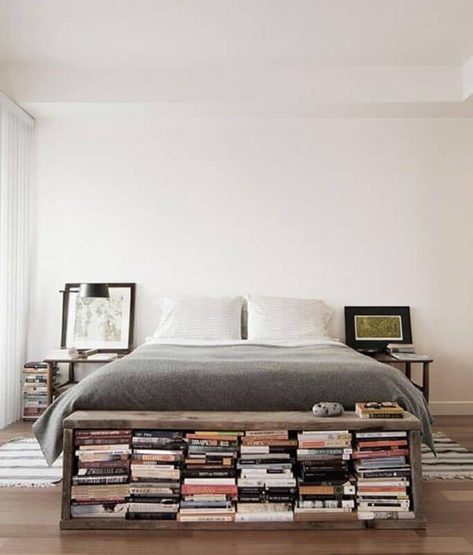 A storage bench at the foot of a bed with lots of books.