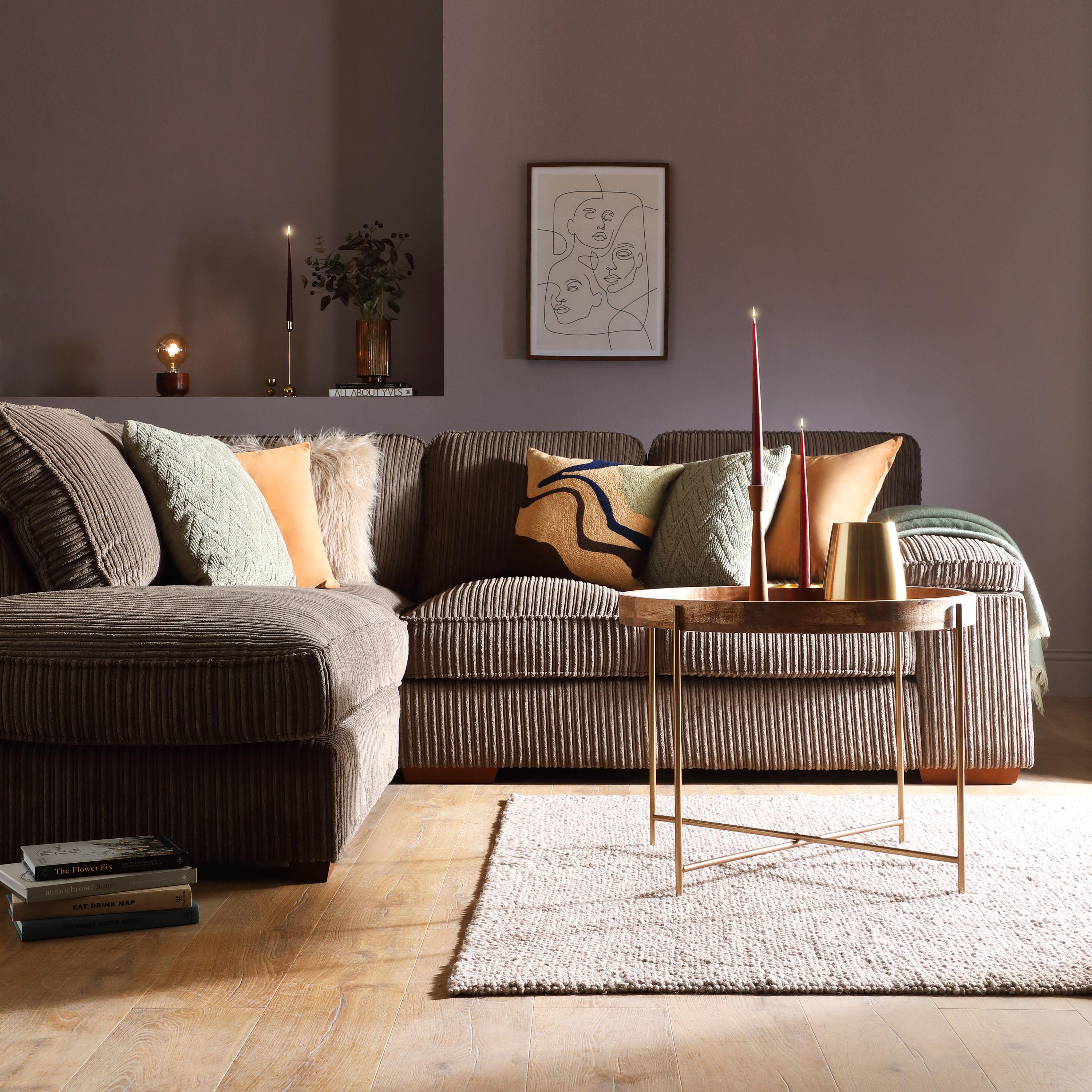 Corduroy corner sofa in a cosy living room with throw pillows and art