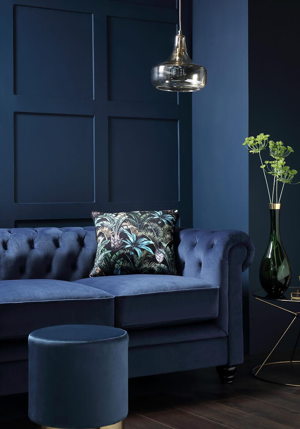 Blue room with blue velvet Chesterfield sofa and leather footstool