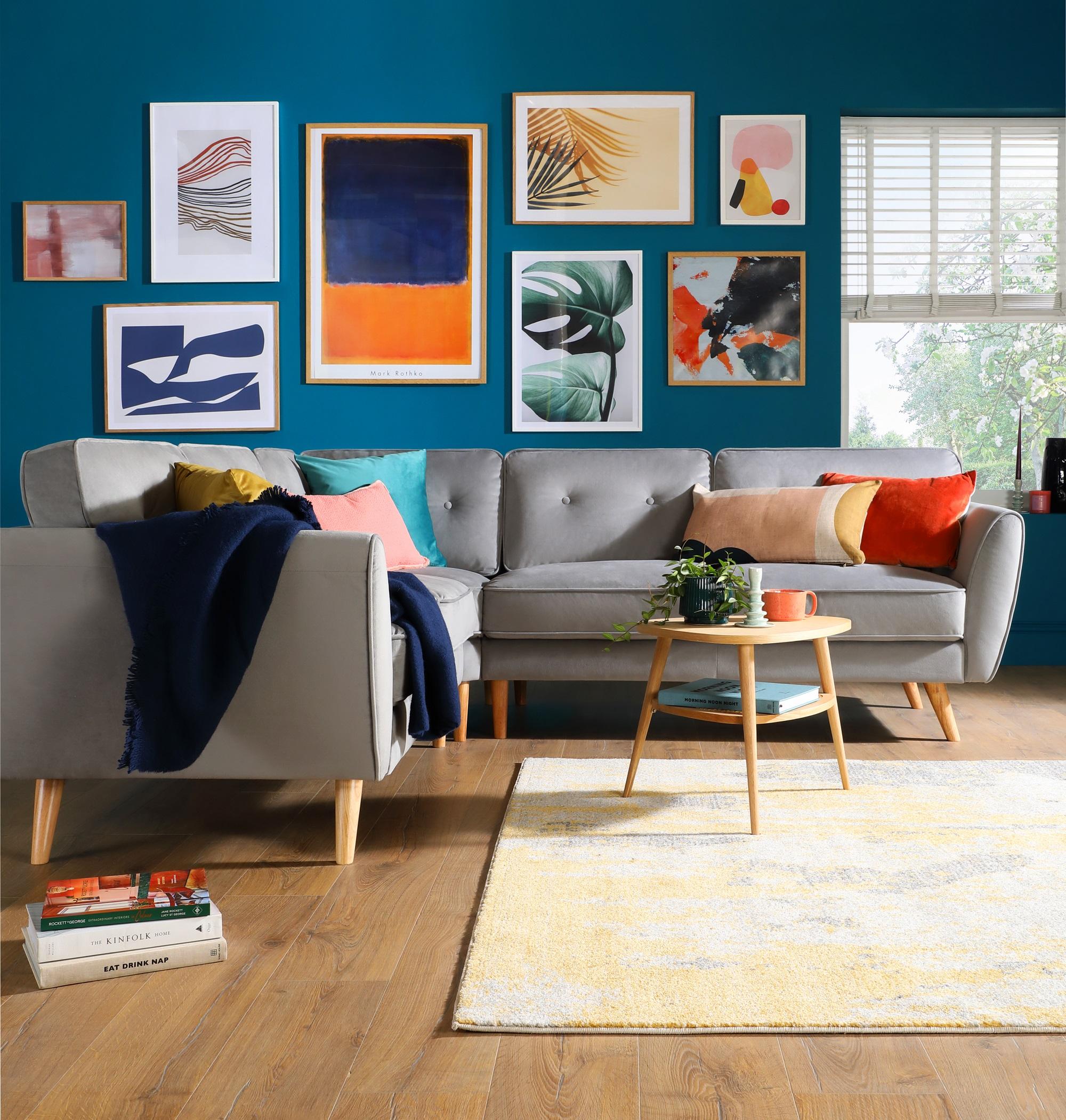 Bright teal gallery wall with grey mid century fabric sofa