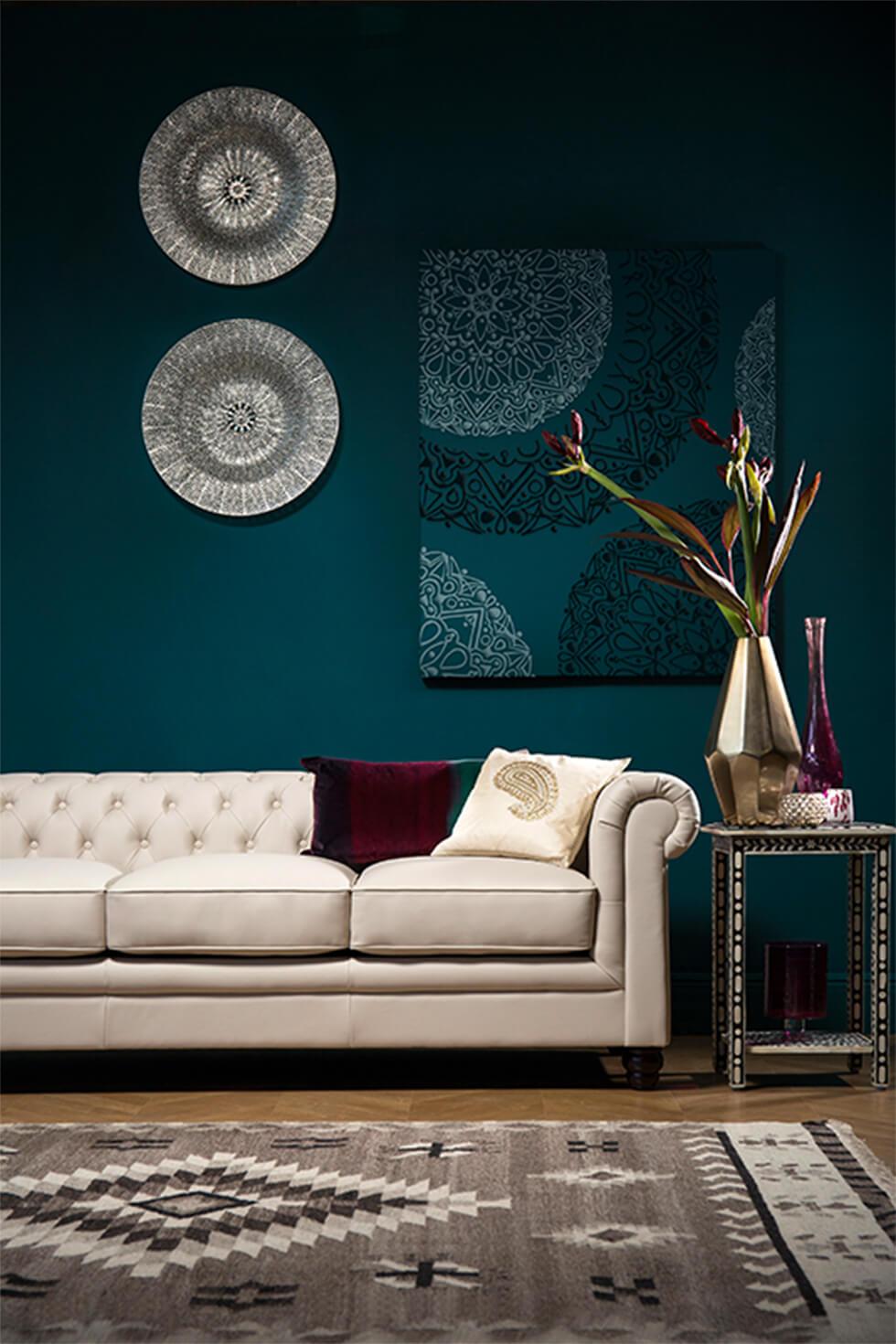 Dark teal living room with global decor and classic white leather Chesterfield sofa