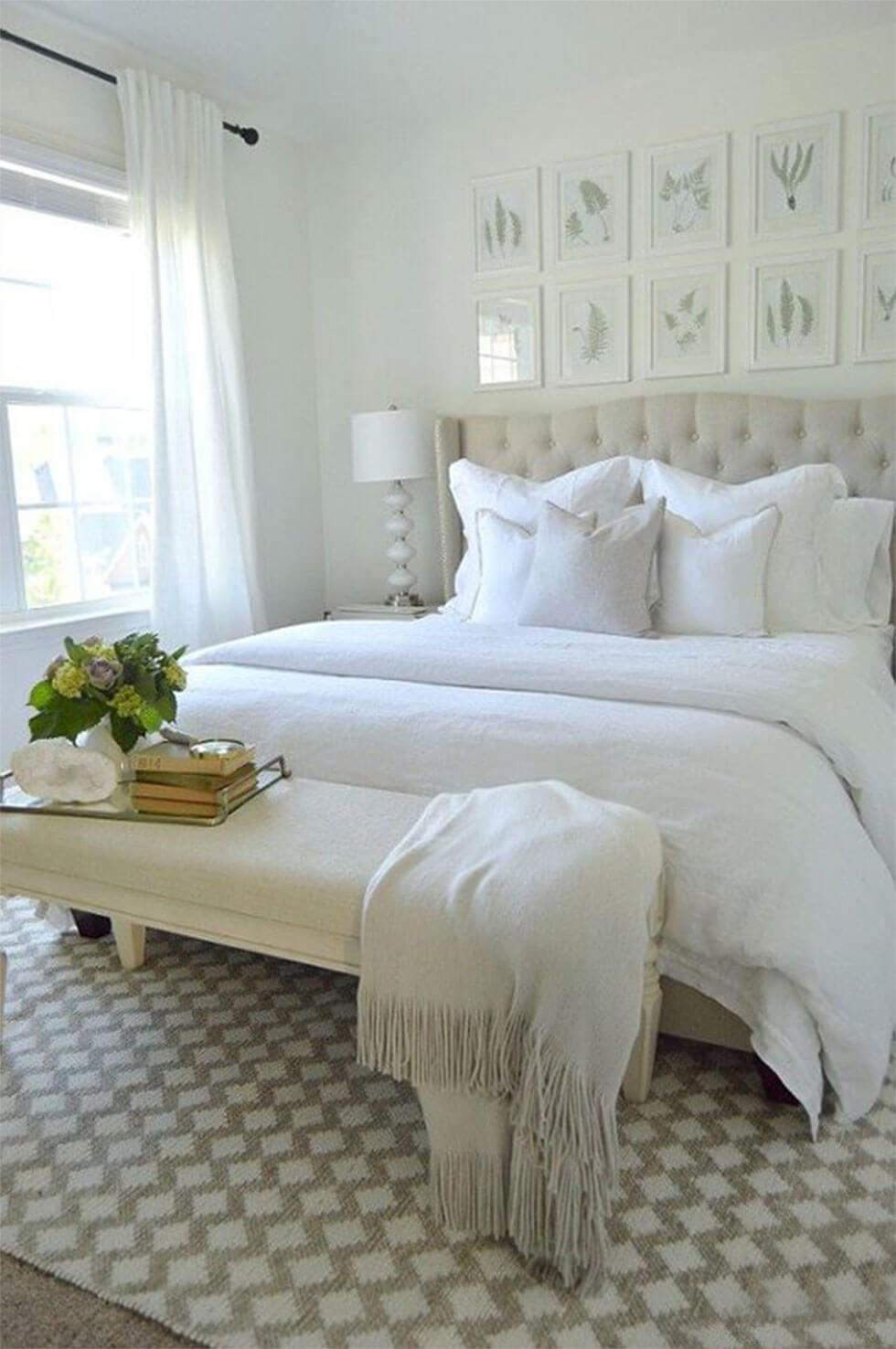 All-white bedroom with tufted headboard, linen bedding and upholstered bench.