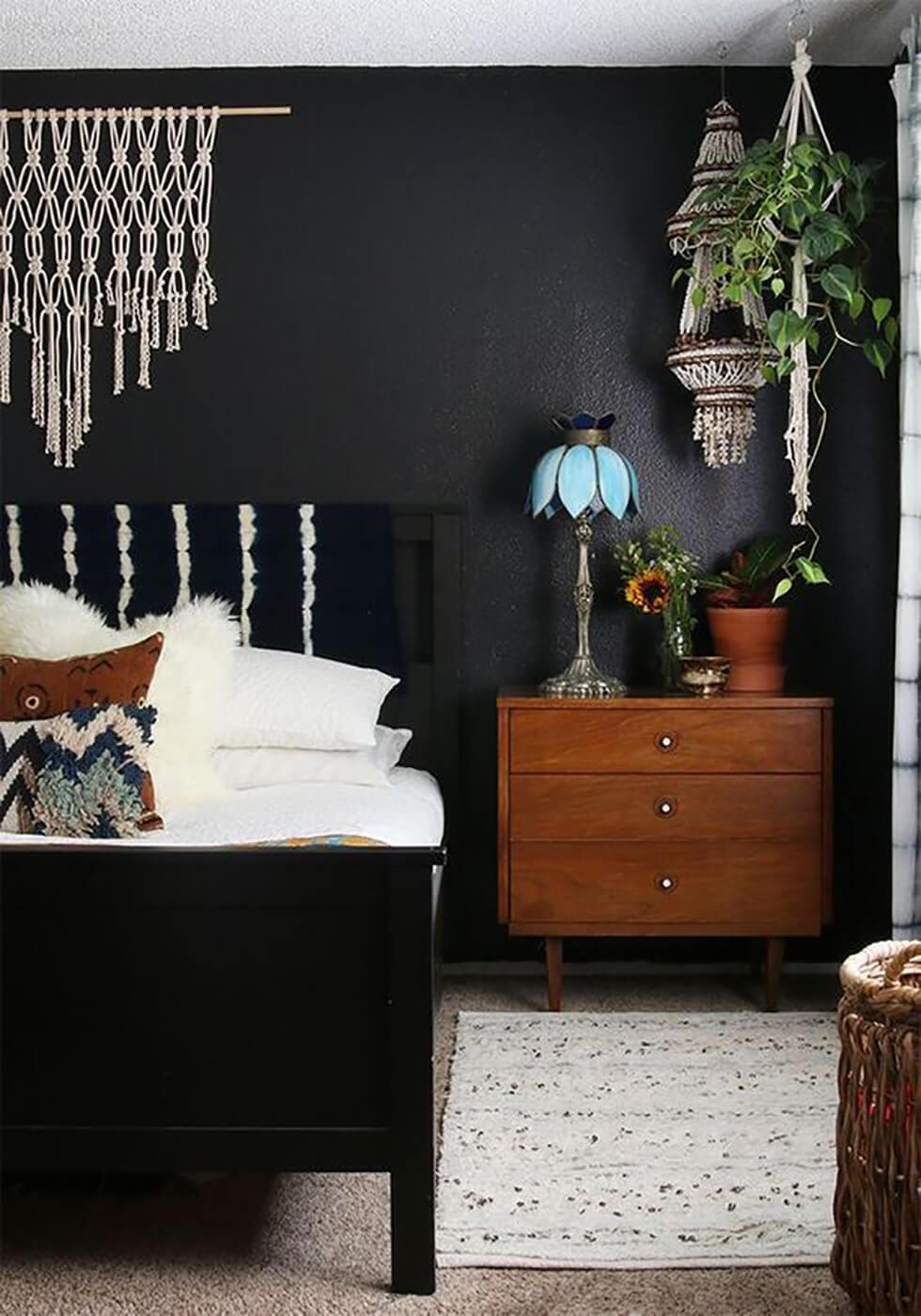 Black and white bedroom in a modern boho style with a black feature wall.